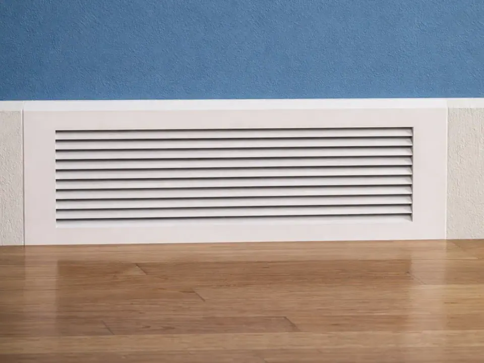 Fitted white replacement vent cover installed along a baseboard